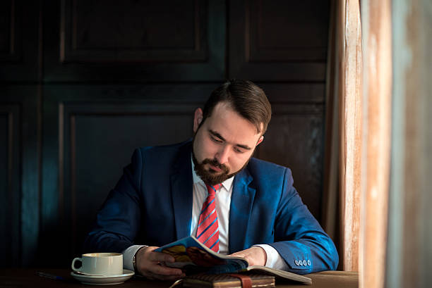 istock young businessman in a cafe reading  magazine 521794688