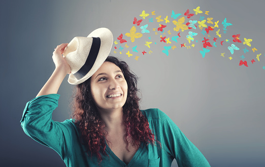 Portrait of  beautiful  girl with hat over head and colorful butterflies flies away