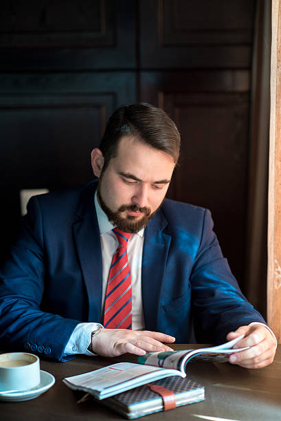 istock young businessman in a cafe reading magazine 521795576