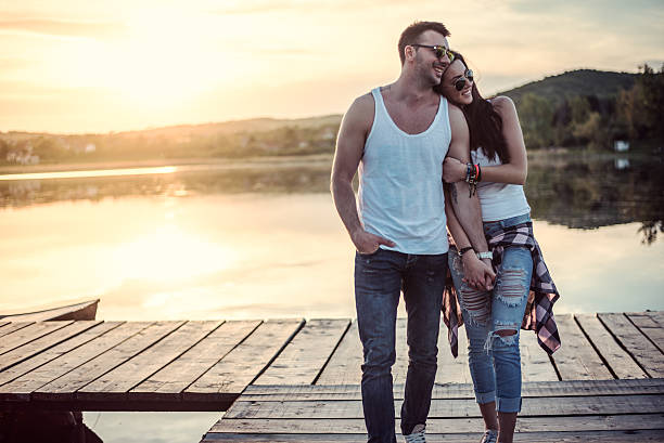 Love couple in nature enjoys on great sunset at the dock by the lake.