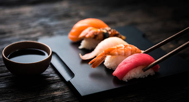 close up of sashimi sushi set with chopsticks and soy - nigiri fotos stockfoto's en -beelden