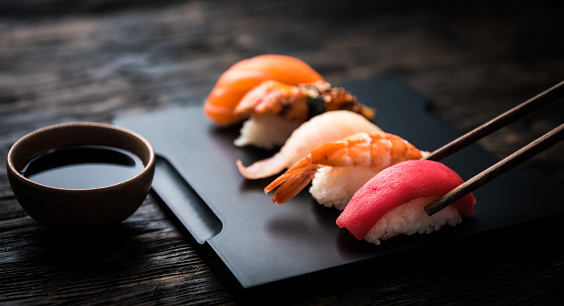 close up of sashimi sushi set with chopsticks and soy on black background