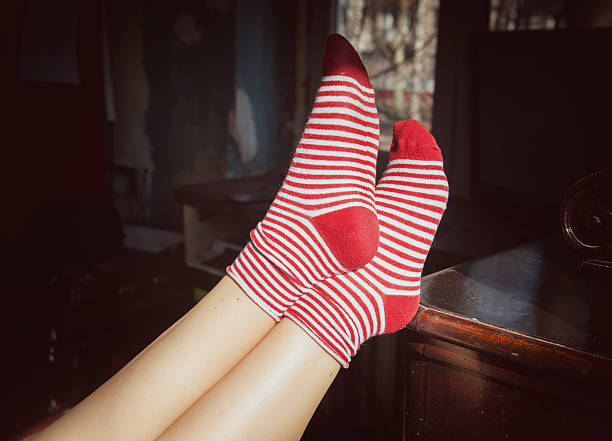 A person wearing jeans with bright classy red loafer shoes with black laces
