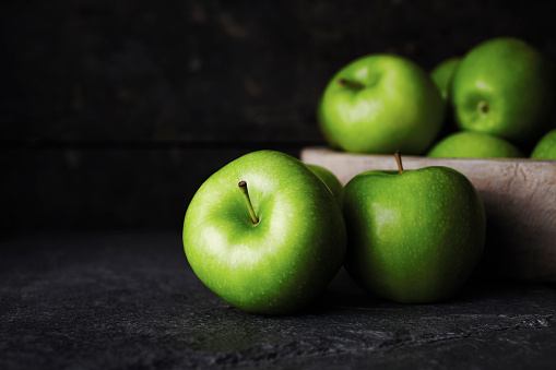 Granny smith apples on granite countertop. 