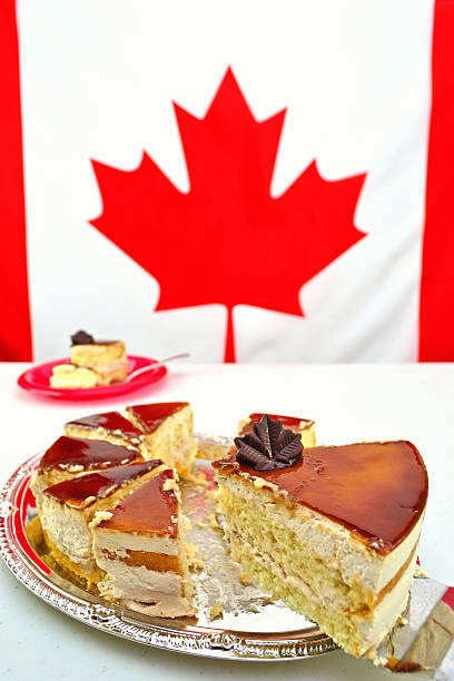 A slice of Maple Mousse Cake for Canada Day celebrations on July 1st. The focus is on the chocolate maple leaf. The Canadian Flag is blurred in the background providing copy space.