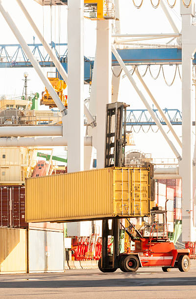 istock Forklift truck loading and unloading shipping containers at port terminal 521808992