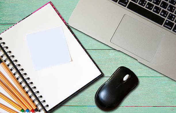 istock Notebook and laptop on wood green texture background 521809734