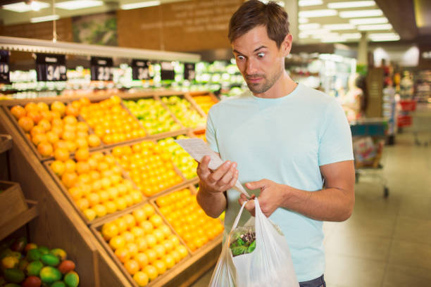 Surprised man reading receipt in grocery store  spending money stock pictures, royalty-free photos & images