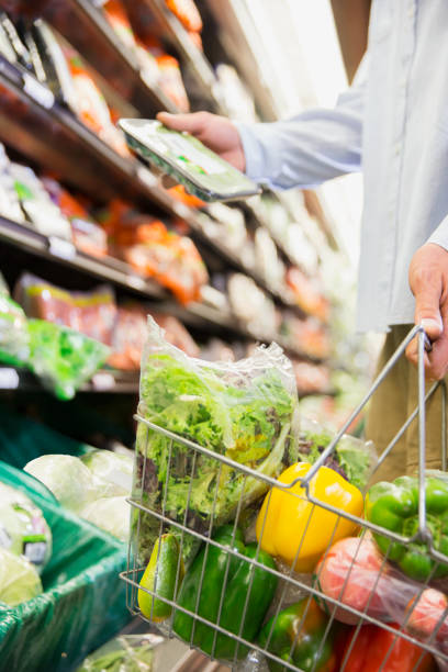 Close up of man holding full shopping basket in grocery store stock photo