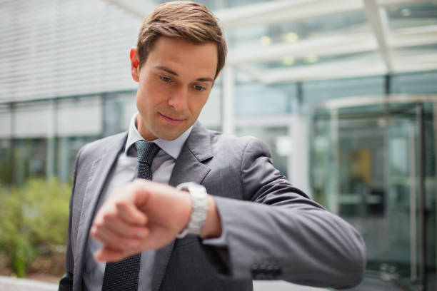 istock Businessman looking at watch outside office building 521811061