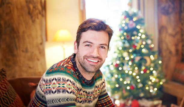 istock Man sitting on couch by Christmas tree 521811175