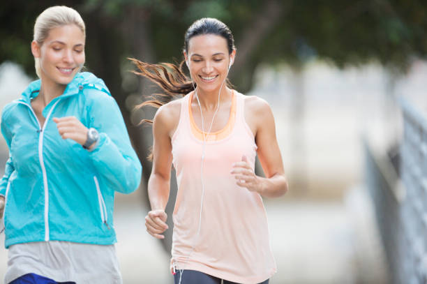 istock Women running through city streets together 521811213