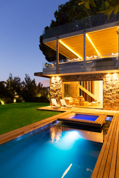 istock Modern house overlooking illuminated swimming pool at night 521811343
