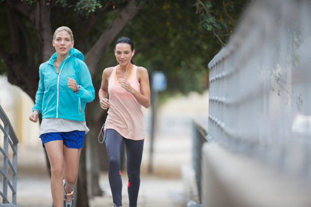 istock Women running through city streets together 521811549