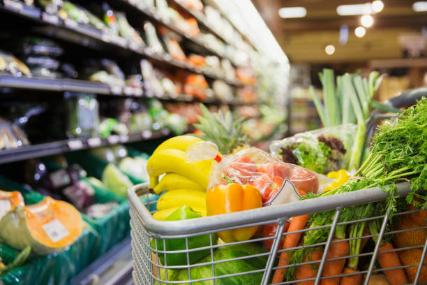 close up of full shopping cart in grocery store - boodschappen stockfoto's en -beelden