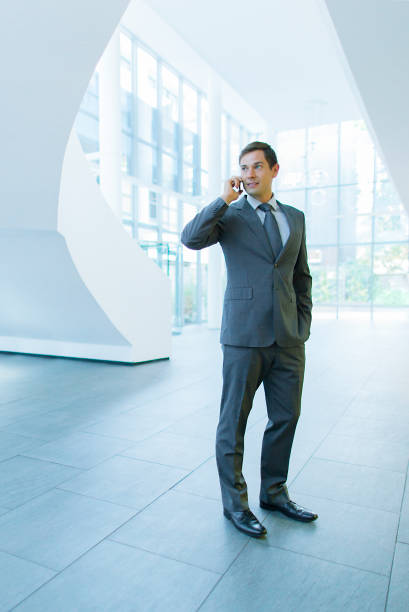 Portrait of thoughtful mature man talking on phone looking up against white background. Horizontal composition. Image taken with Nikon D800 and developed from Raw format.