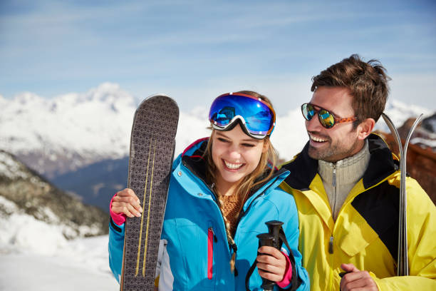 pareja sosteniendo esquís juntos - snow gear fotografías e imágenes de stock