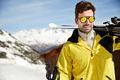 Man carrying skis on mountain top