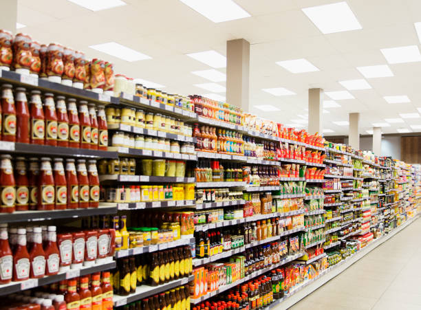 bestückte regale im supermarktgang - condiment stock-fotos und bilder