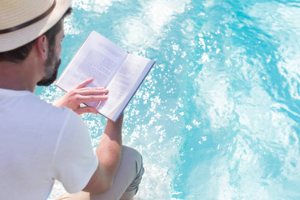 istock Man reading book over swimming pool 521812399