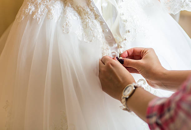 istock Bridesmaid is helping the bride to dress 521812904