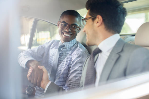istock Smiling businessmen shaking hands in car 521812933