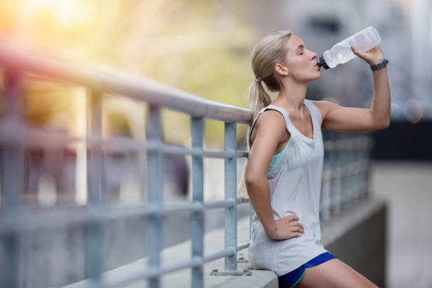 mulher bebendo água depois de se exercitar na rua da cidade - water bottle sports and fitness selective focus sport - fotografias e filmes do acervo