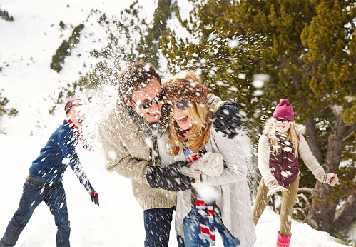 Snowball fight. Winter couple having fun playing in snow outdoors. 