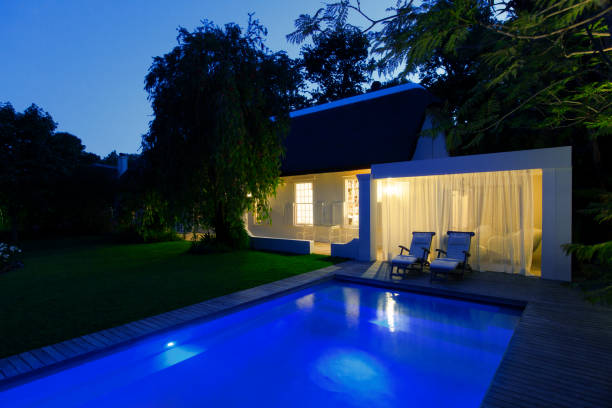 istock Modern house overlooking illuminated swimming pool at night 521813261