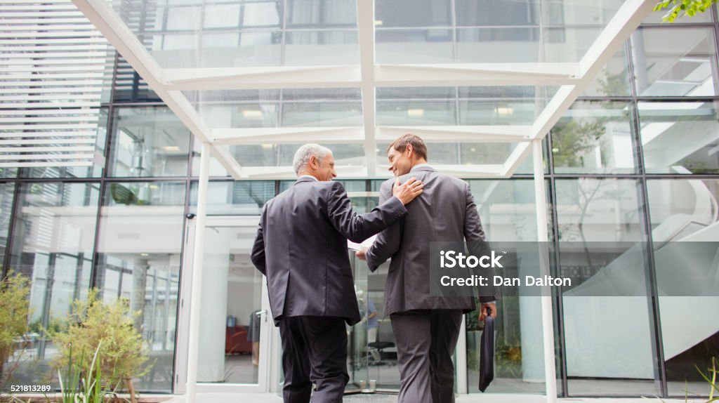Businessmen walking into office building together  Walking Stock Photo