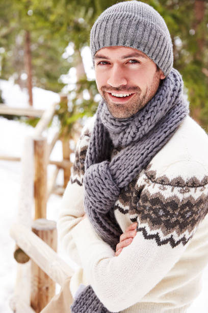 istock Smiling man sitting on snowy fence 521813525