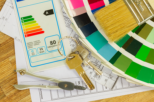 Interior designer's working desktop with  energy rating chart, architectural plan of the house, color palette and  brushes