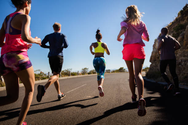 Multi-ethnic group of young adult athletes wearing sports clothing running outdoors on summer