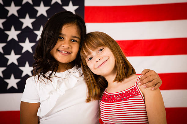 duas meninas feliz abraçar em frente da bandeira dos estados unidos da américa - child flag fourth of july little girls imagens e fotografias de stock