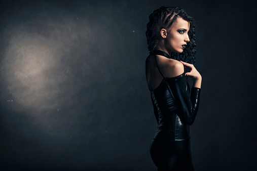 Low key portrait of a young mysterious woman wearing latex clothing.
