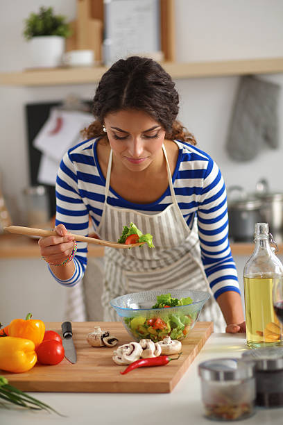 istock Young woman eating fresh salad in modern kitchen 521821405