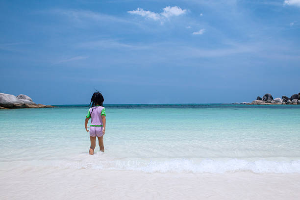 istock Little girl walking alone at beach 521828019