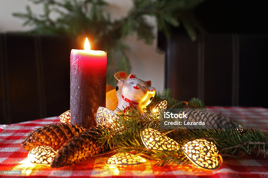 New Year home decoration with maneki neko and candle. Happy New Year home decoration with maneki neko, candle and christmas tree on the dinner table. Atmospheric Mood Stock Photo