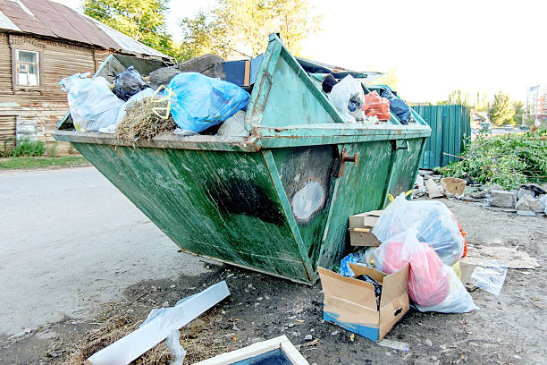 istock Overfilled trash dumpster in ghetto against slum houses 521849697