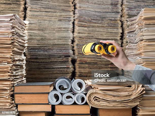 Binoculars In Human Hand And Searching Messy Library Stock Photo - Download Image Now