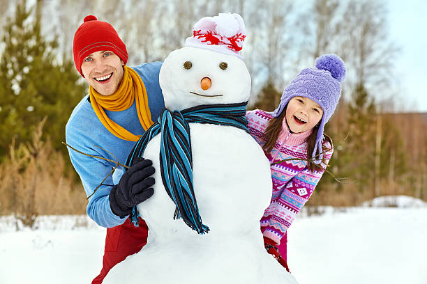 istock Father and daughter with snowman 521852243