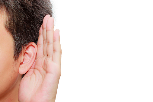 Asian man holds his hand near his ear and listening