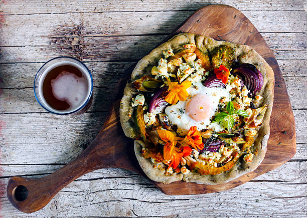 Pizza with root vegetables, cottage cheese, egg and flowers stock photo