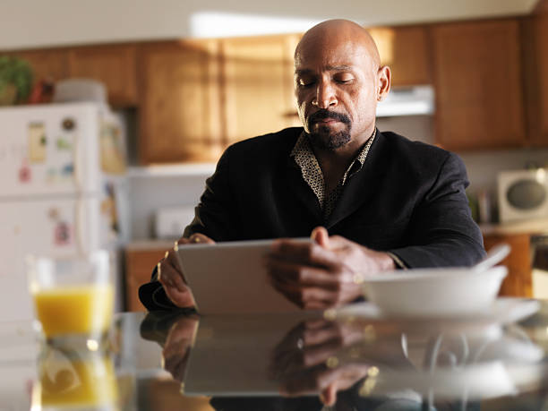istock mature african man with tablet in kitchen and breakfast 521888493