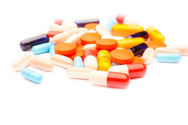 pilules colorées, tablettes et de capsules sur fond blanc - injecting capsule macro pill photos et images de collection