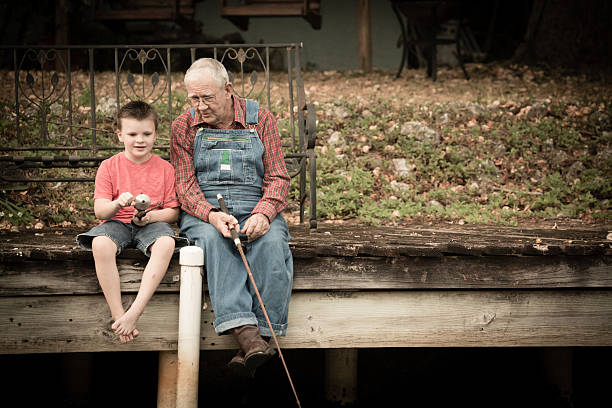 großvater mit seinem enkel fischen auf hölzernen dock - great grandson stock-fotos und bilder