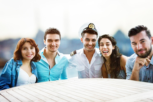 Group of friends portrait on a yacht with captain. Low ISO with some grain visible.