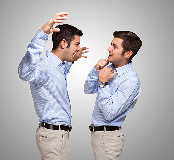 istock Man attacking a frightened clone of himself 521936751
