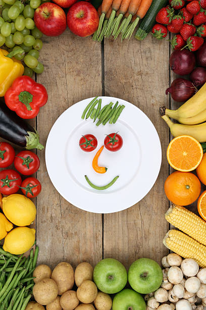 istock Smiling face from vegetables and fruits on plate with tomatoes 521953019