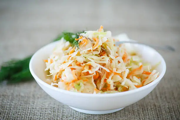 pickled cabbage and carrots in a white plate on the table